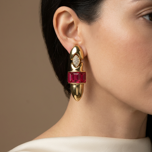 AI-styled on-ear editorial image of Pannetta earring with pomegranate-red stones and downward-pointing gold end